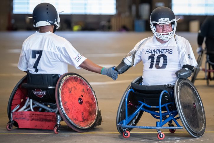 Two athletes from the Hammers team showing camaraderie as they pass each other.