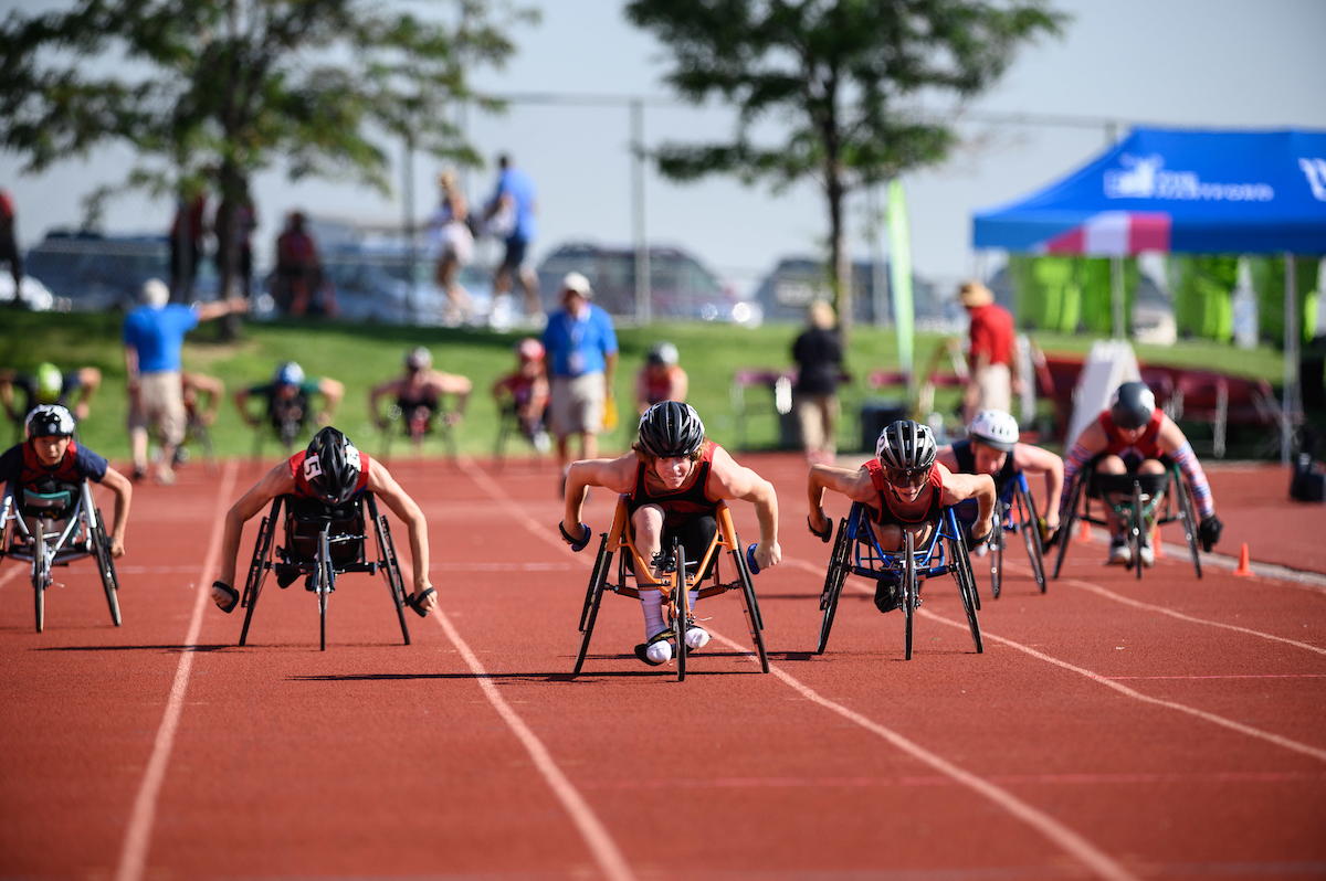Athletes competing in racing wheelchairs coming up the track.