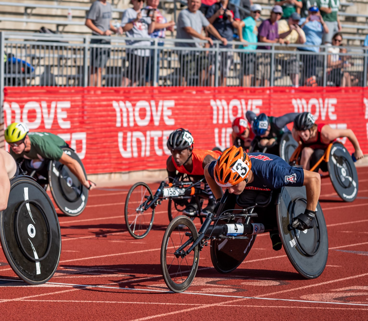 Athletes in racing wheelchairs competing on a track
