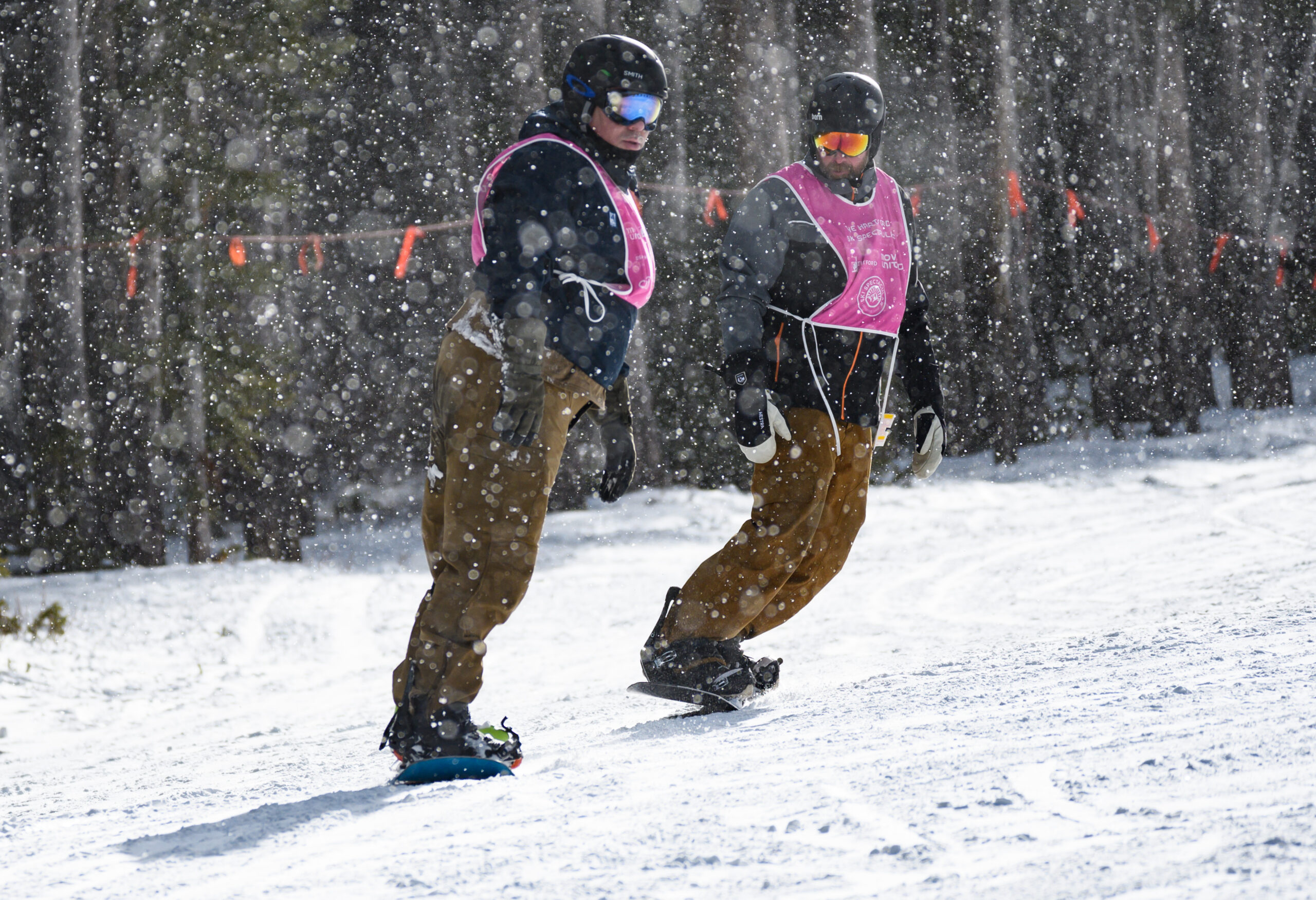 Two people snowboarding with heavy snow coming down