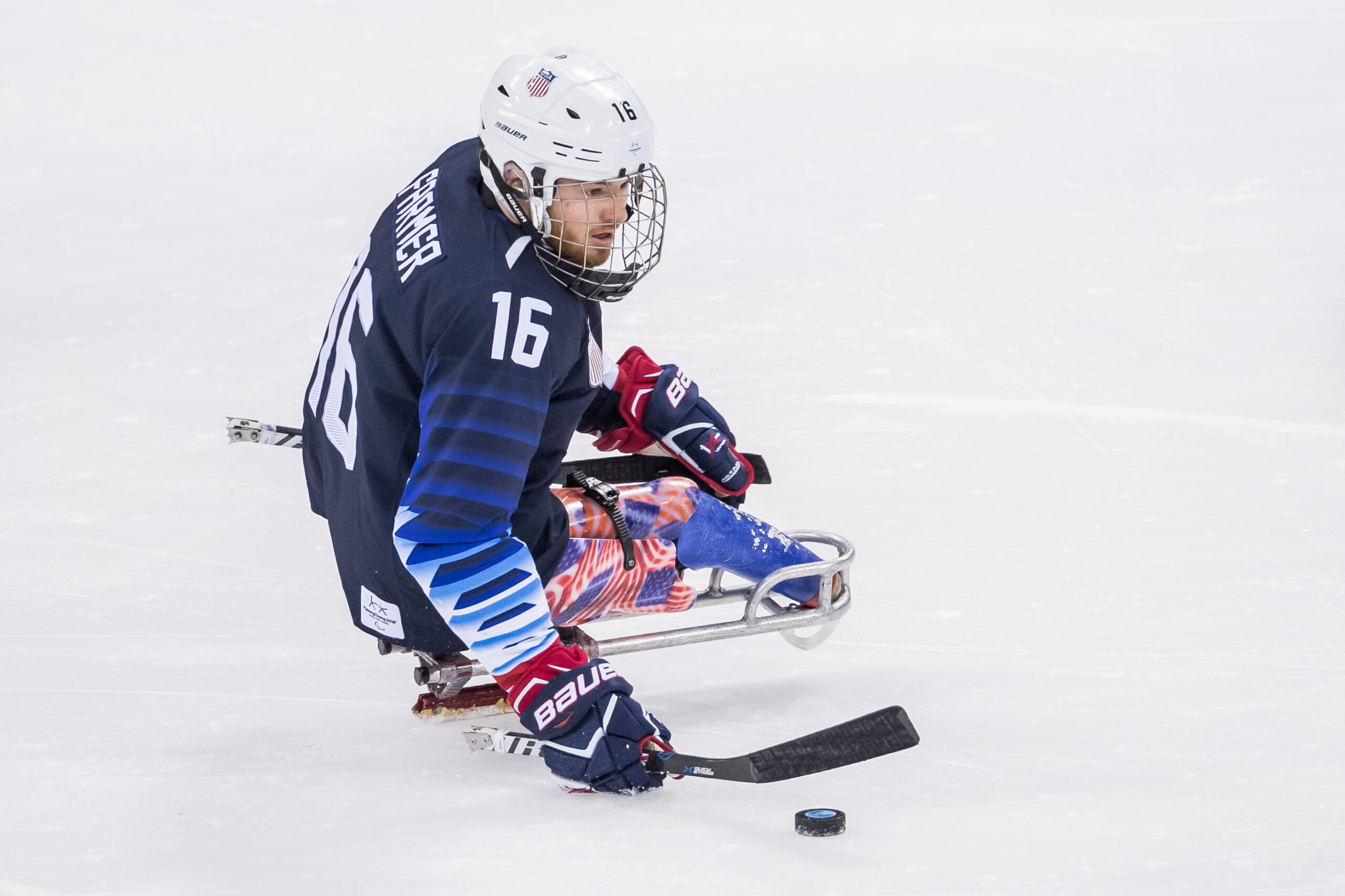 Sled Hockey Player on the ice getting ready to hit the puck with his stick