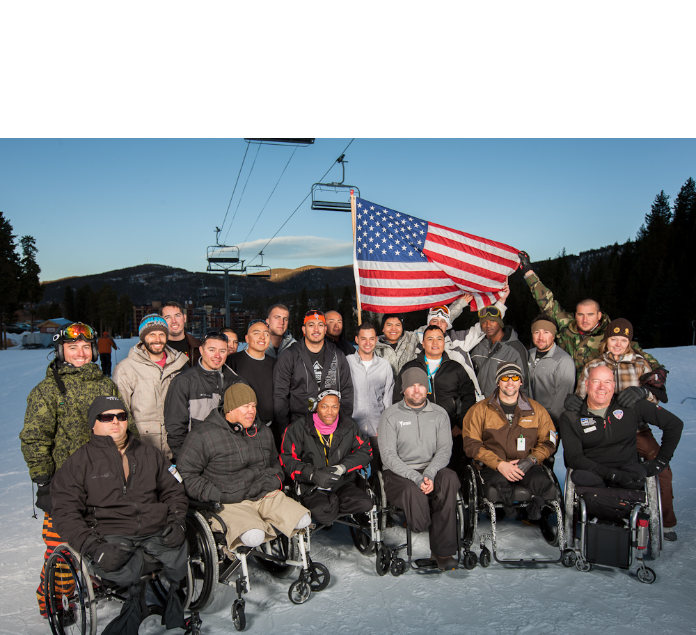 Group of wounded warfighters posing for picture in the snow with USA flag in background