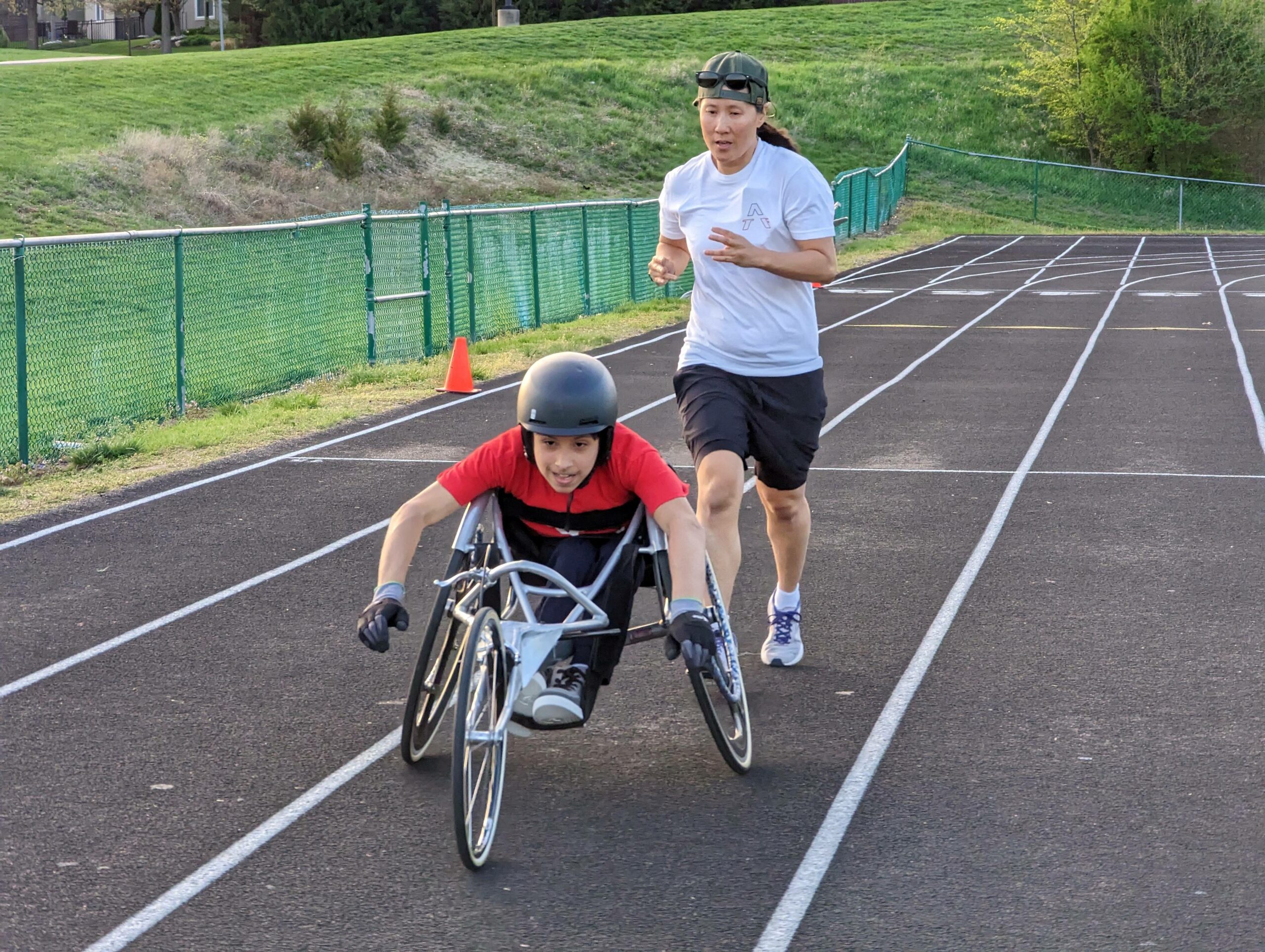 Two people on a track, one running and one in an athletic wheelchair