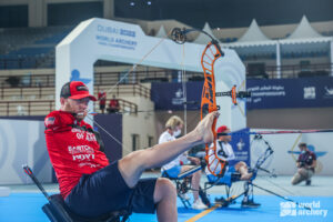 A person competing in adaptive archery and shooting with their feet