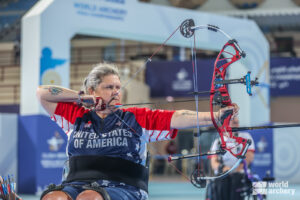 A person competing in archery at an indoor competition