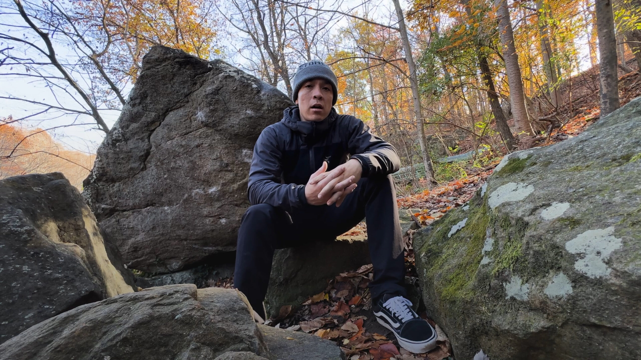 Jared Lenahan sitting on a rock looking at the camera wearing a hat and a jacket