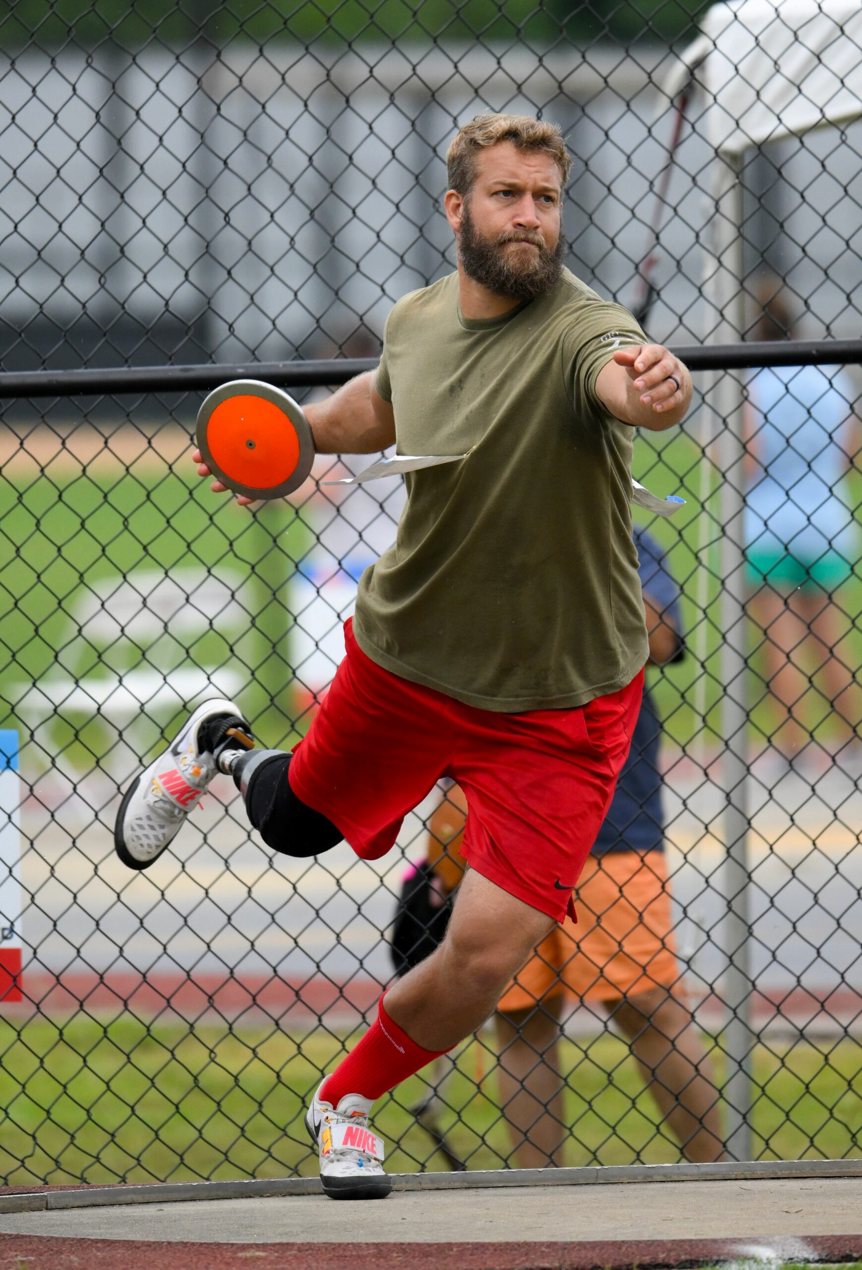 Athlete in discus ring with discus in hand about to throw. Athlete mid-spin before releasing the discus.