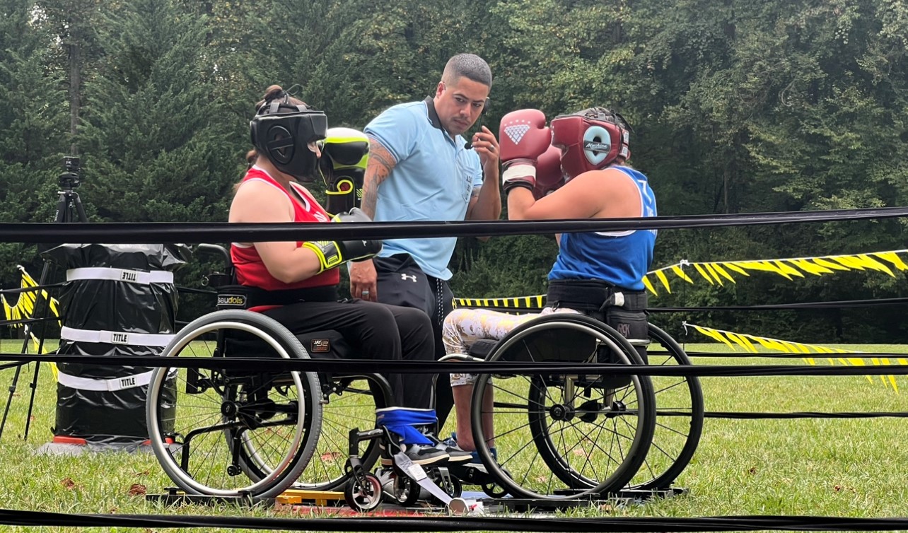 Two individuals who are wheelchair users actively engaged in boxing match
