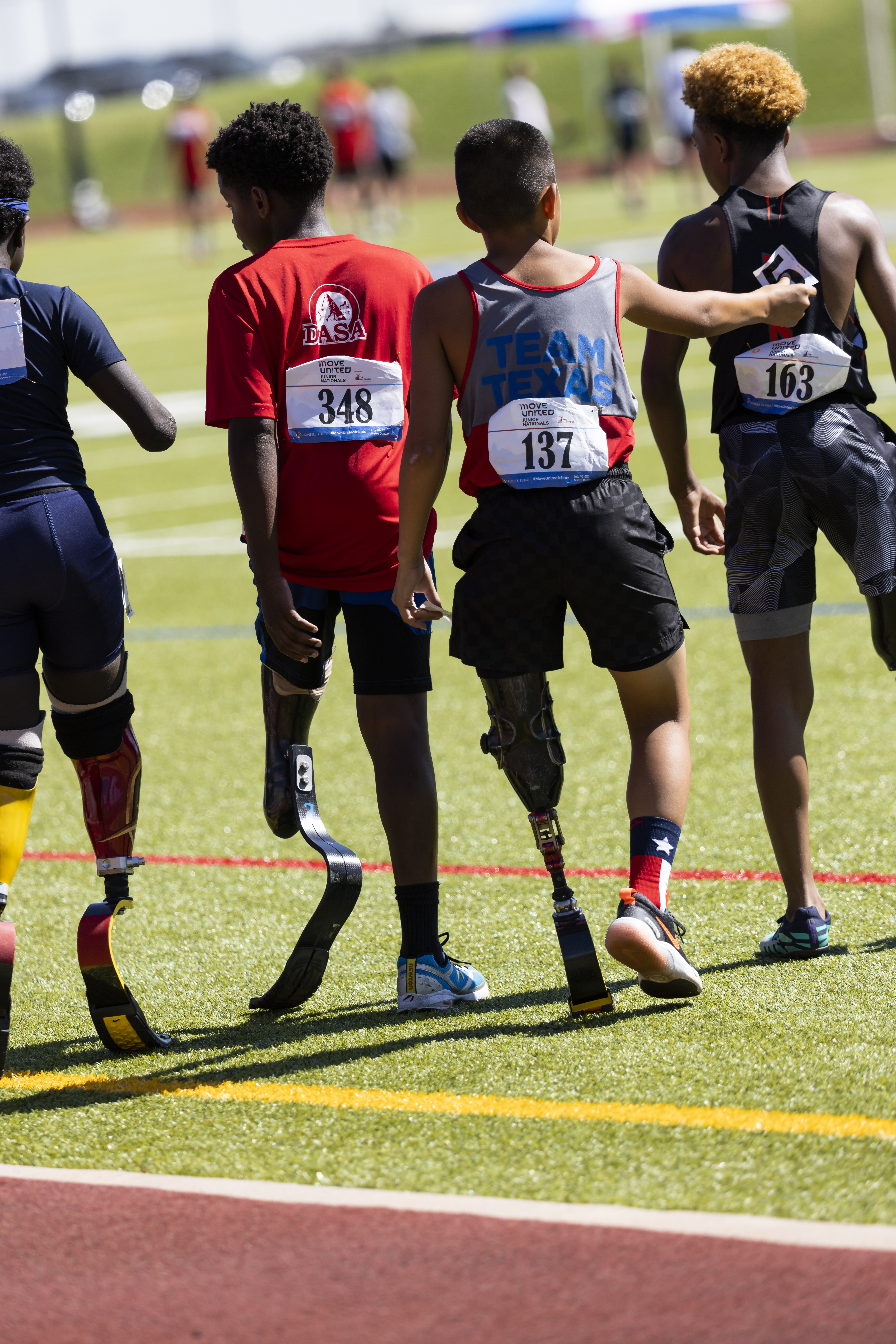 4 adaptive athletes walking away from the camera.