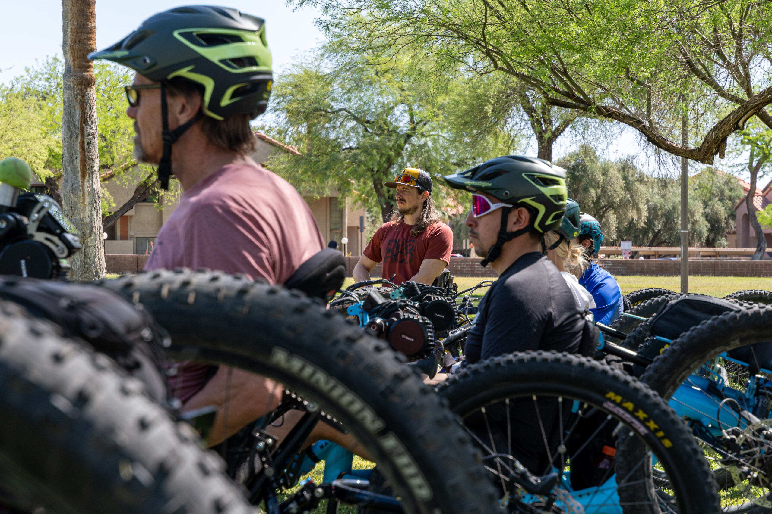side view of several workshop participants on adaptive mountain bikes looking at instructor