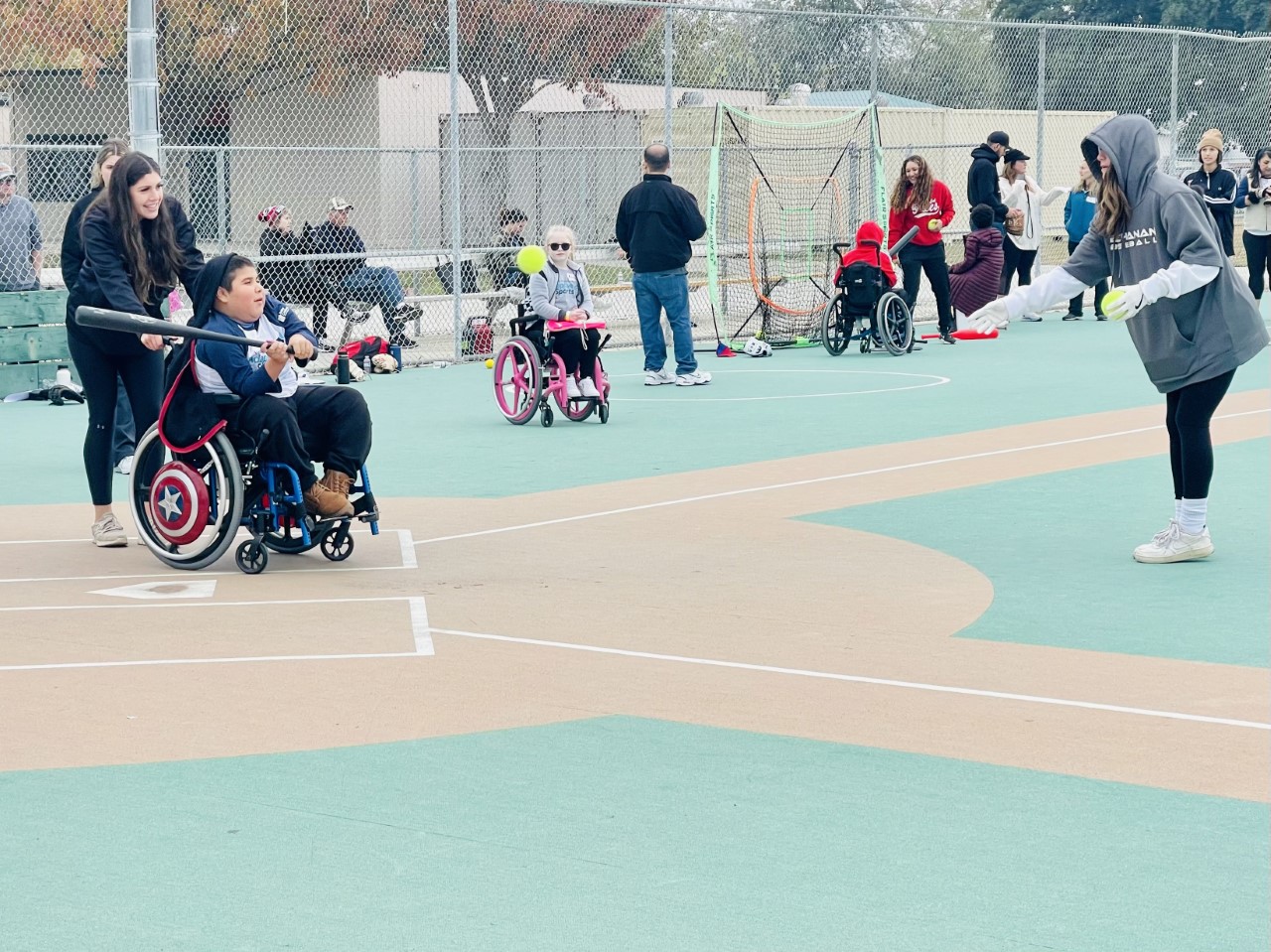 An athlete in a wheelchair swings the bat at an oncoming softball