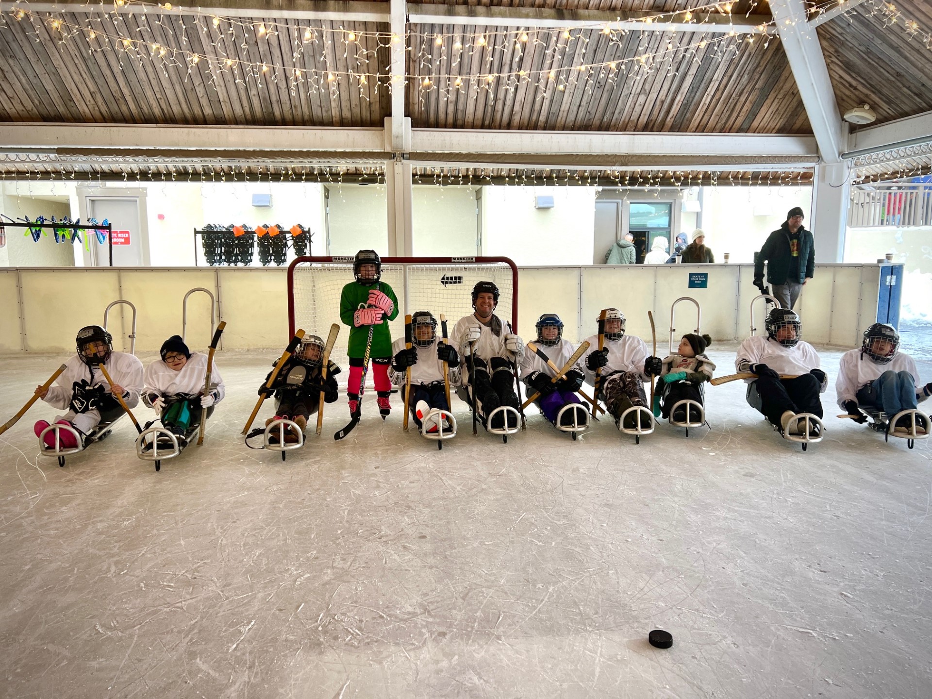 A team of sled hockey players pose on the ice for a picture.