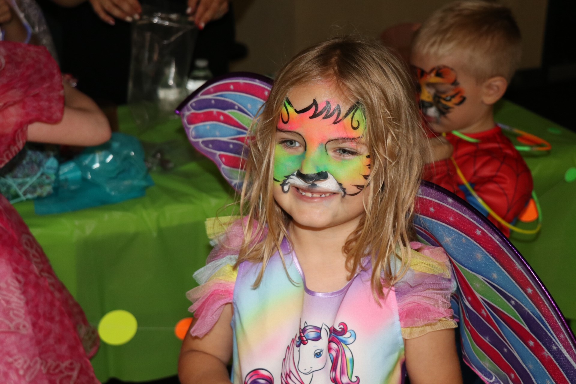 A young child with their face painted smiles for the camera.