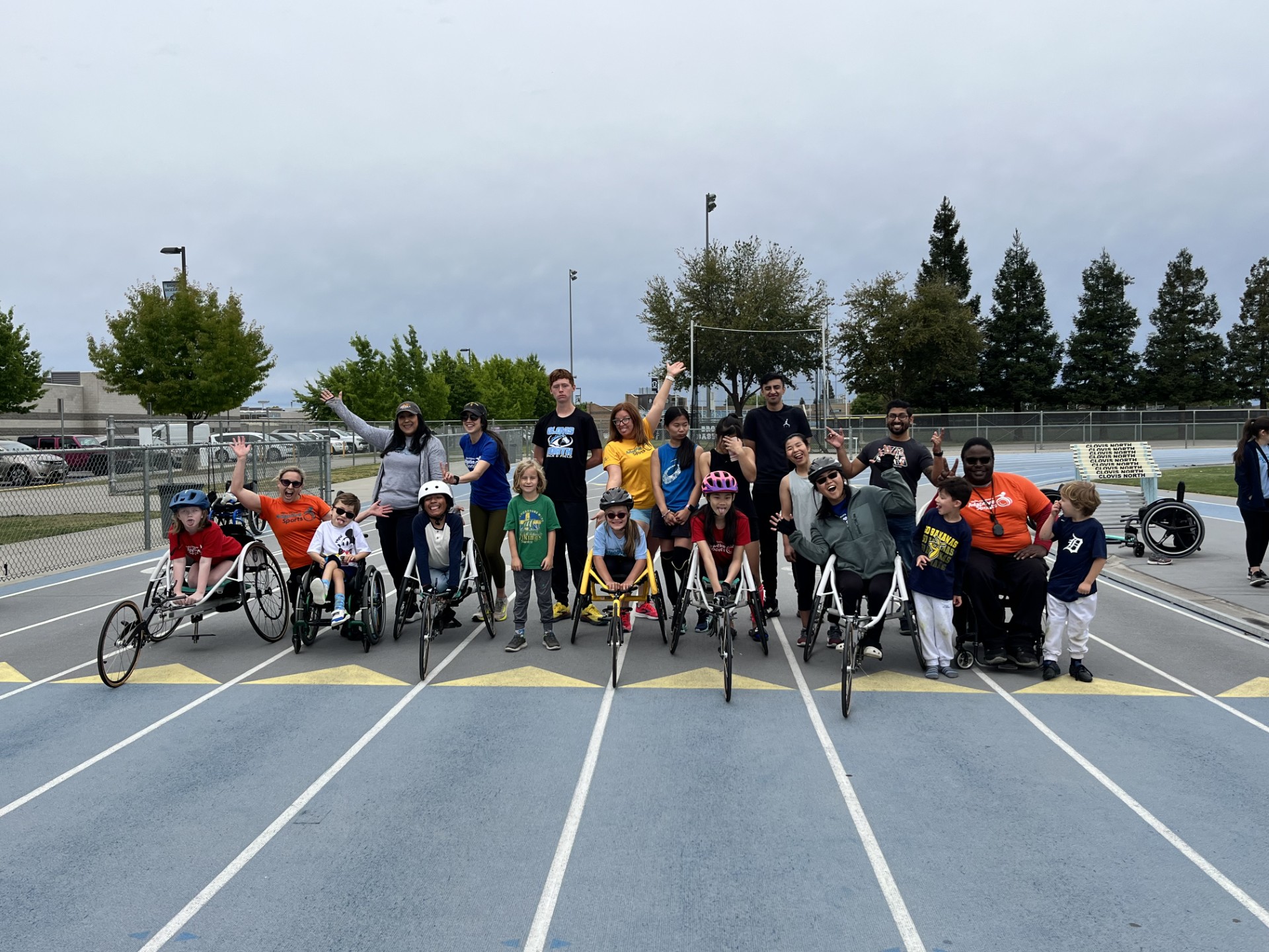 A group of athletes stand and sit together for a picture on the blue track.