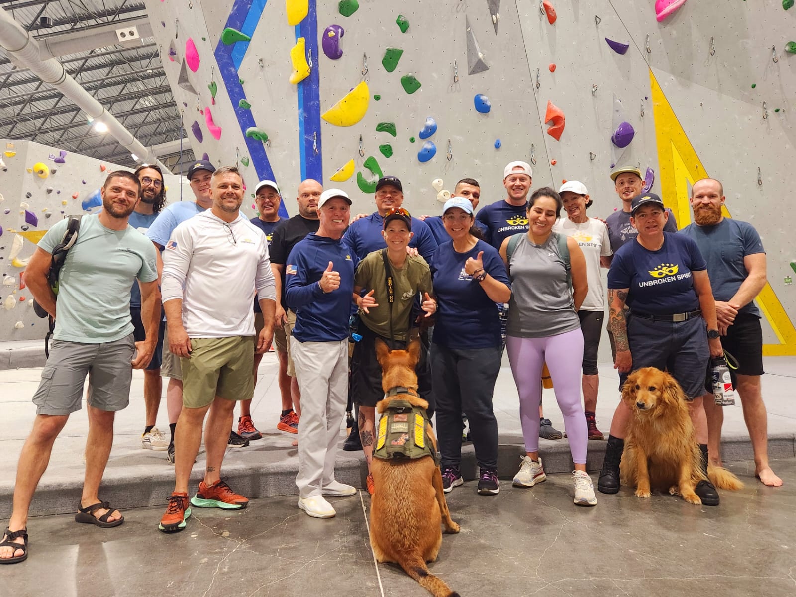 A group of individuals smile for a picture in front of an indoor climbing wall