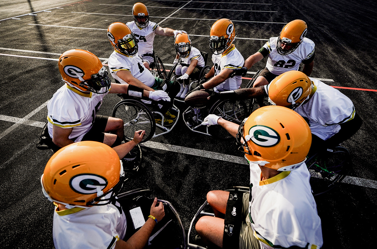 Green Bay Packers Wheelchair Football Team athletes in a huddle with their hands together in the middle