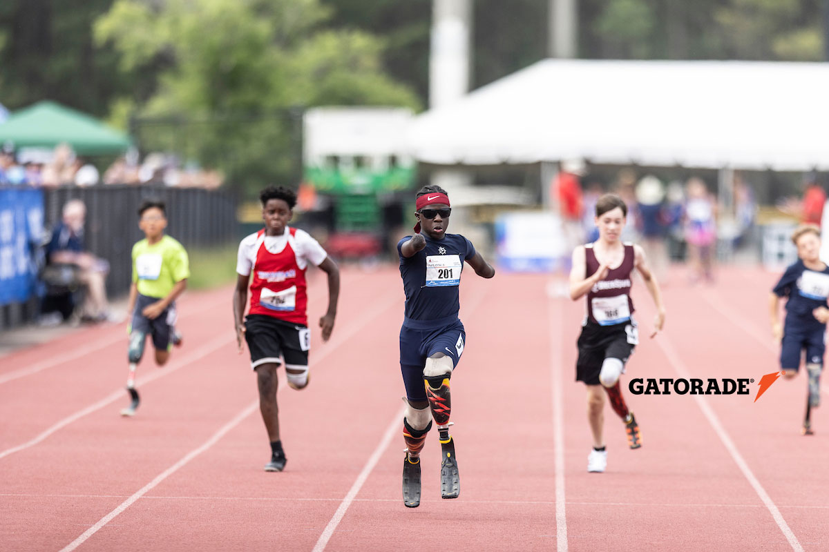 Youth athletes with disabilities running down a track towards you.