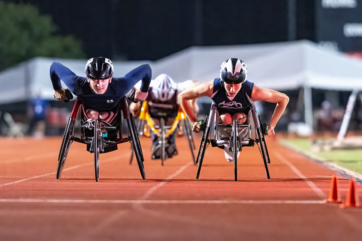 3 wheelchair track athletes headed down the straightaway