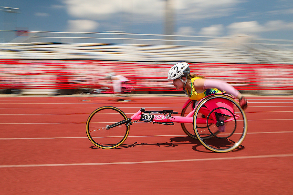 Sideview of young wheelchair racer headed down straitaway on track