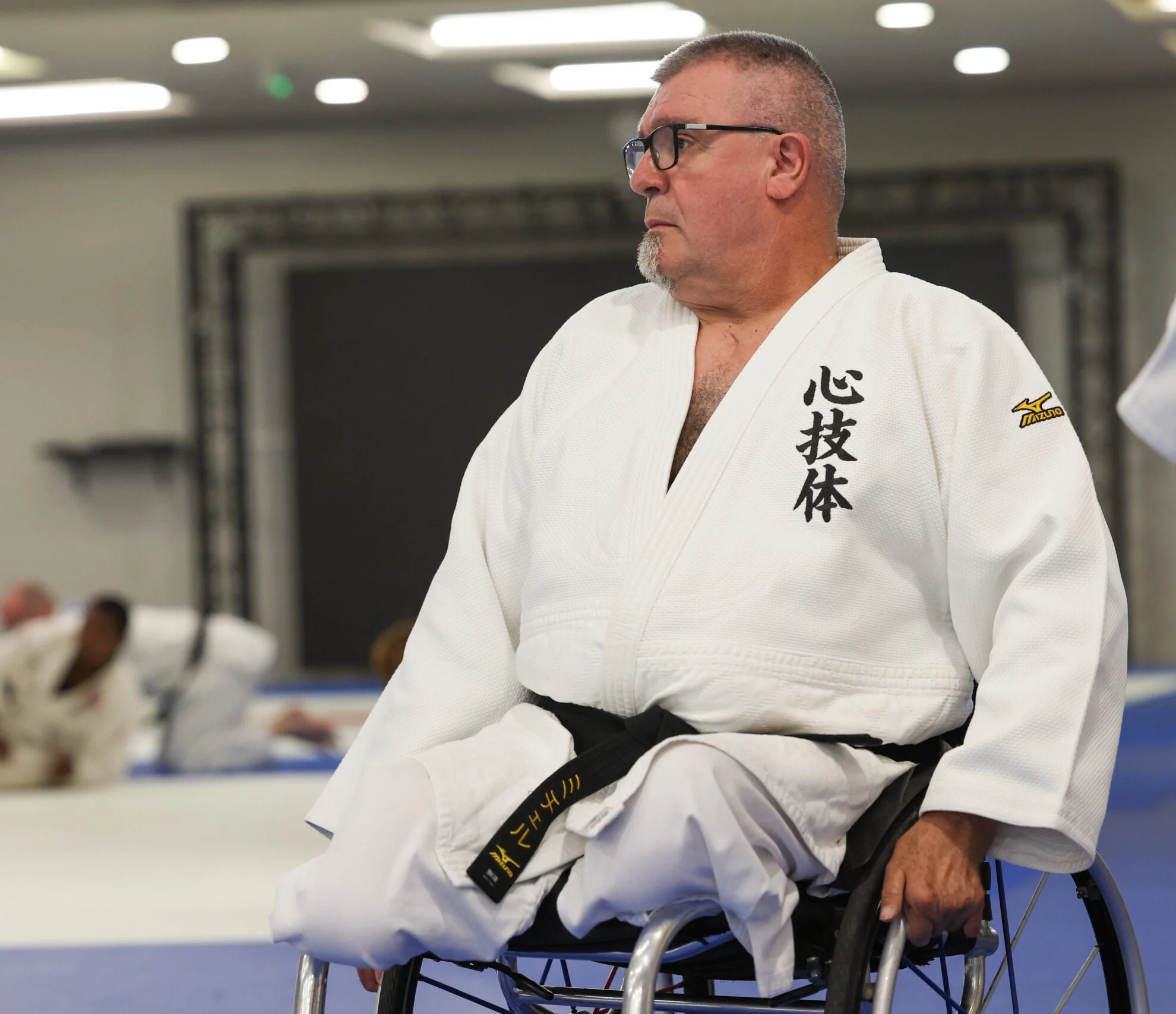 Judo athlete sitting in wheelchair on mat