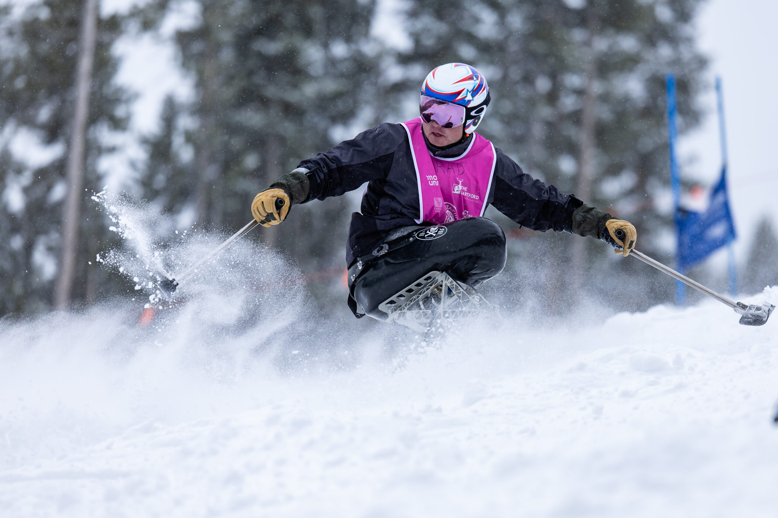 An adaptive athlete skiing down a snowy mountain