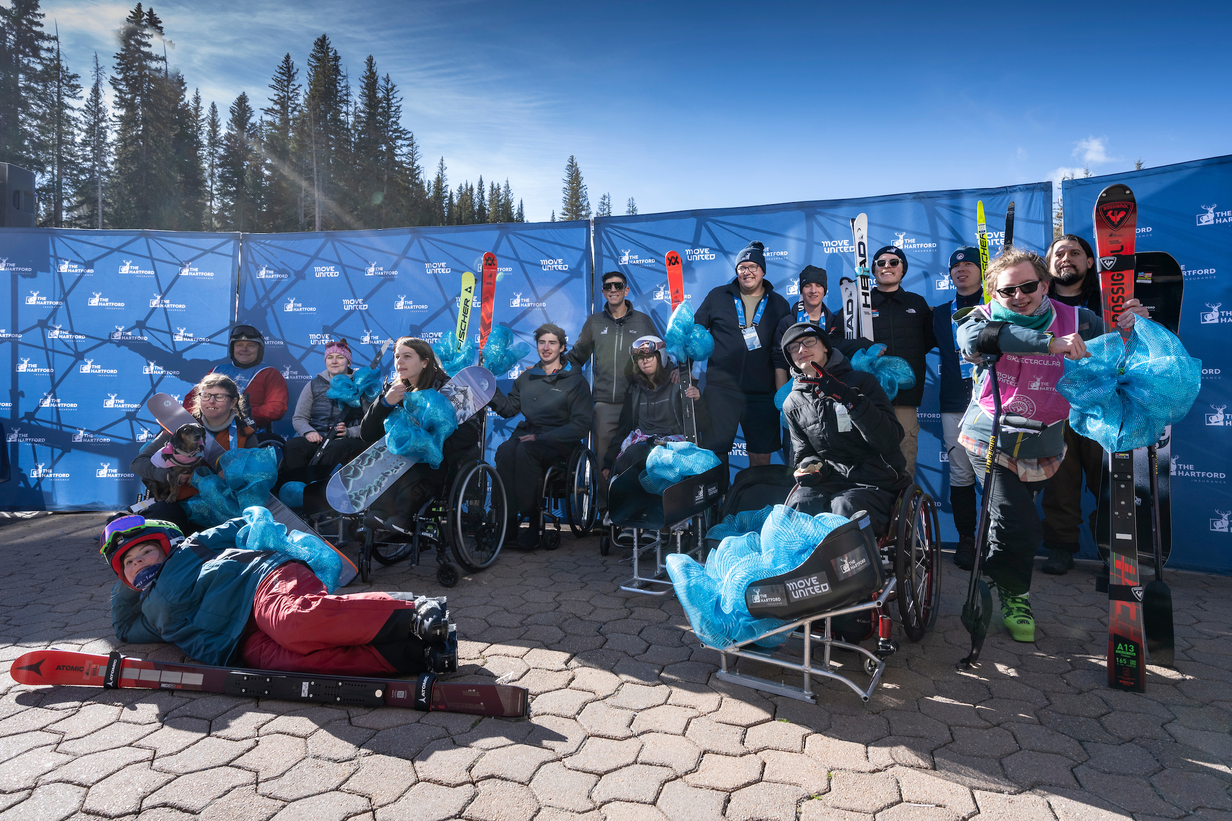Group of equipment recipients holding their equipment in front of a Ski Spec background