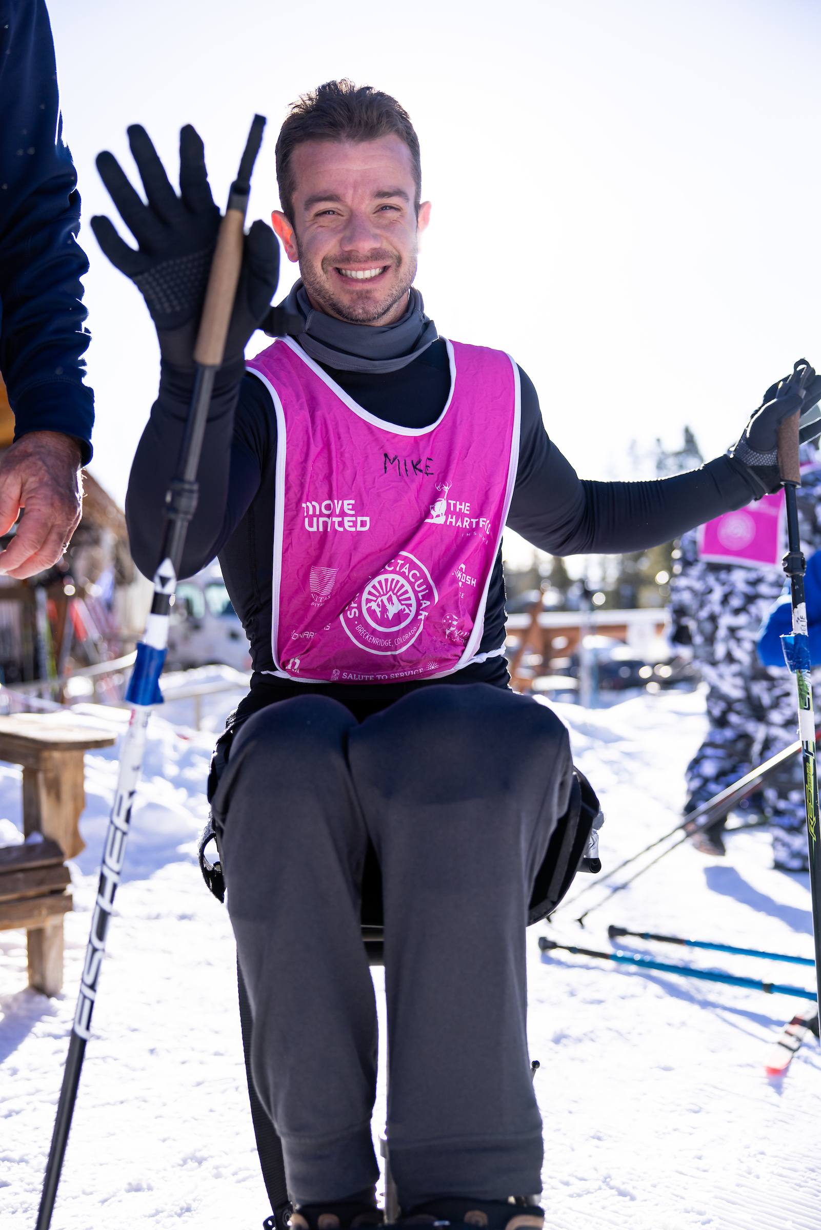 Adaptive sit skier waving to the camera