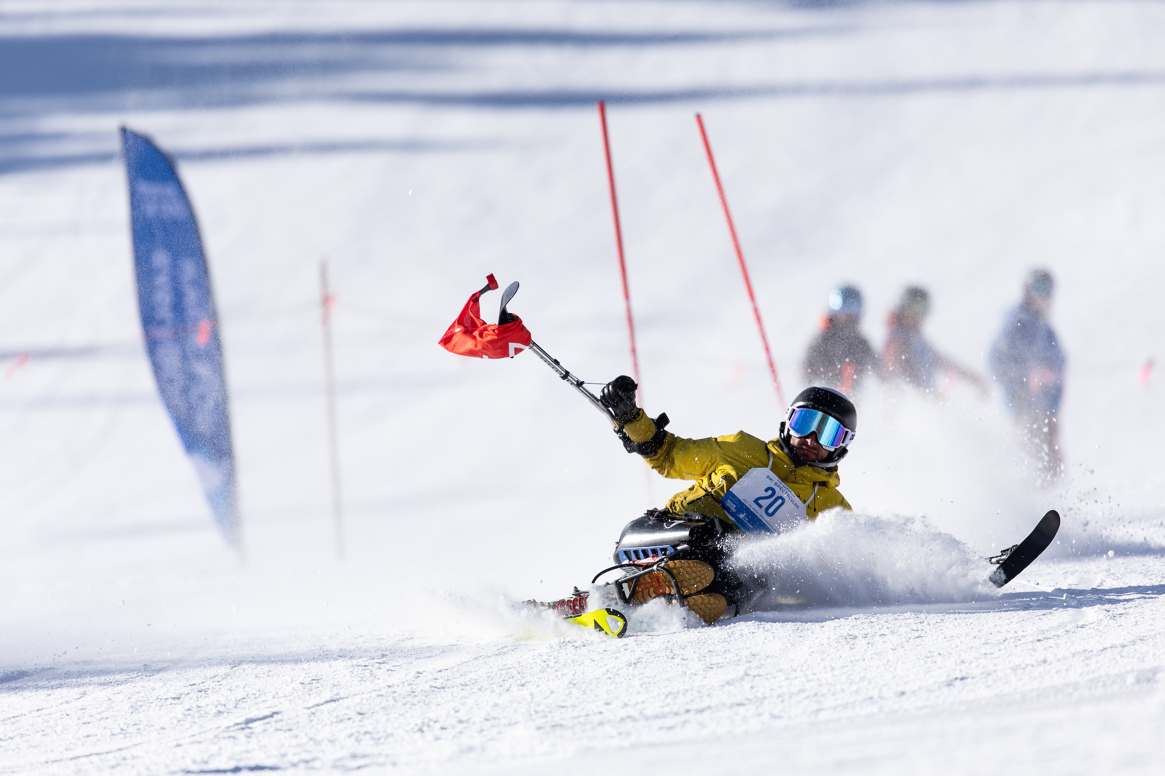 Sit skier going down a race course in between panels