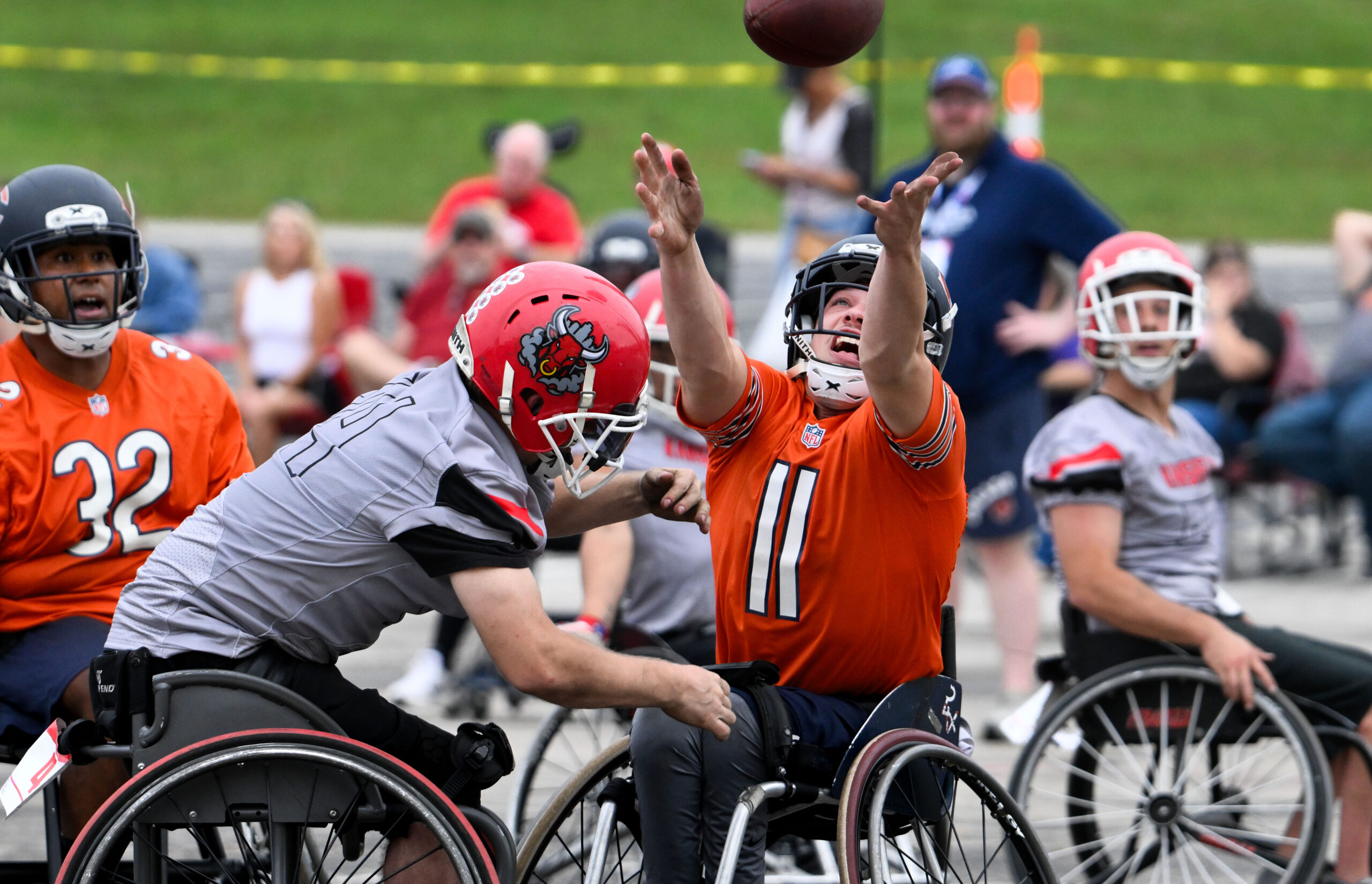 Chicago Bears athlete reaching for a pass in wheelchair football game.