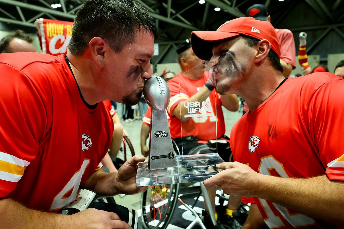 Kanas City Chiefs Wheelchair football team athletes kissing the 2025 season championship trohpy