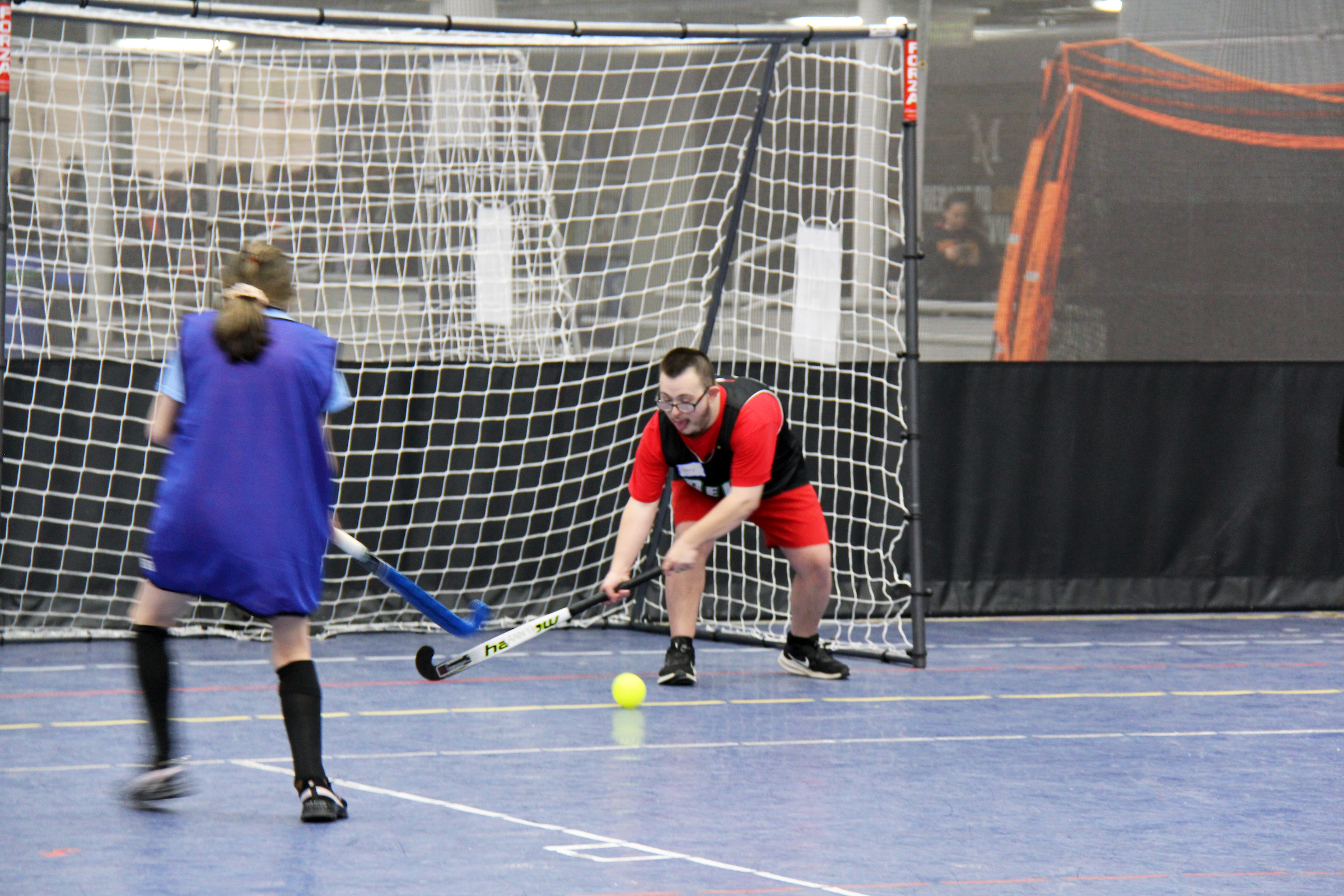 Athlete swinging their field hockey stick to hit a yellow ball
