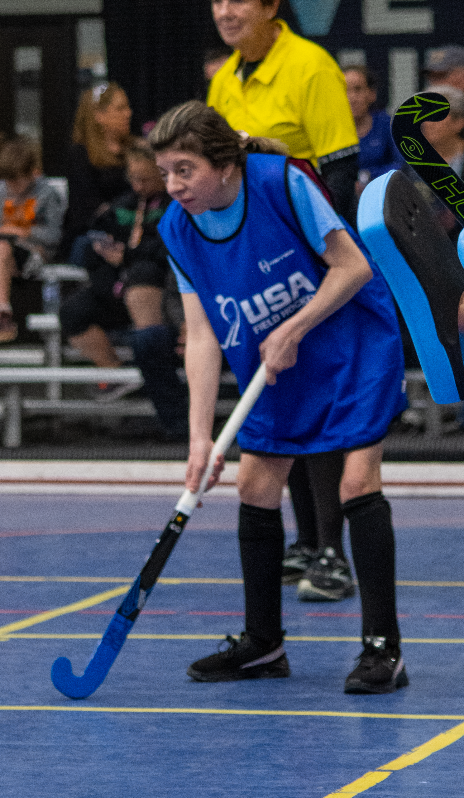 Athlete stands with field hockey stick on the ground.