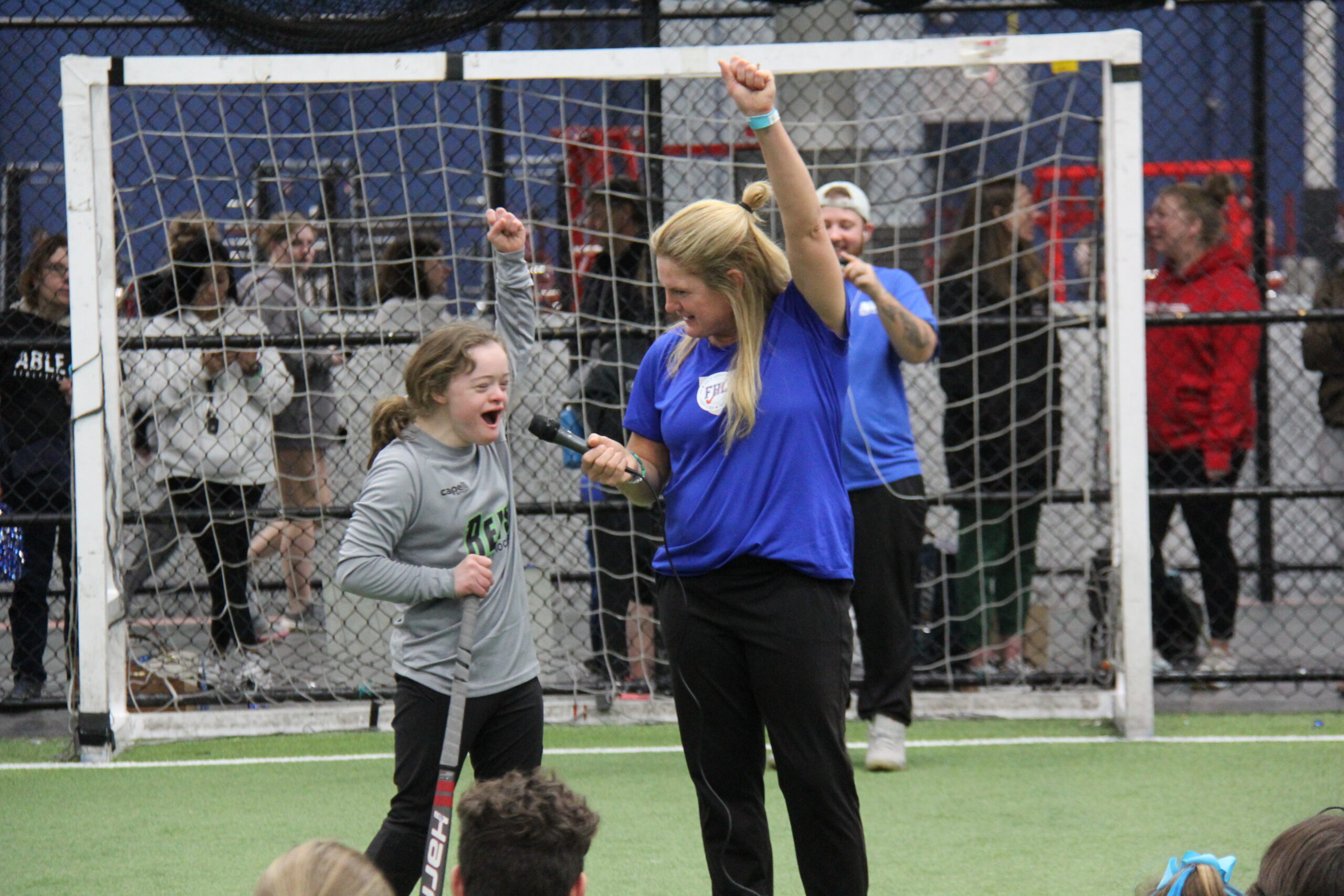 Athlete cheers through microphone while standing next to coach.