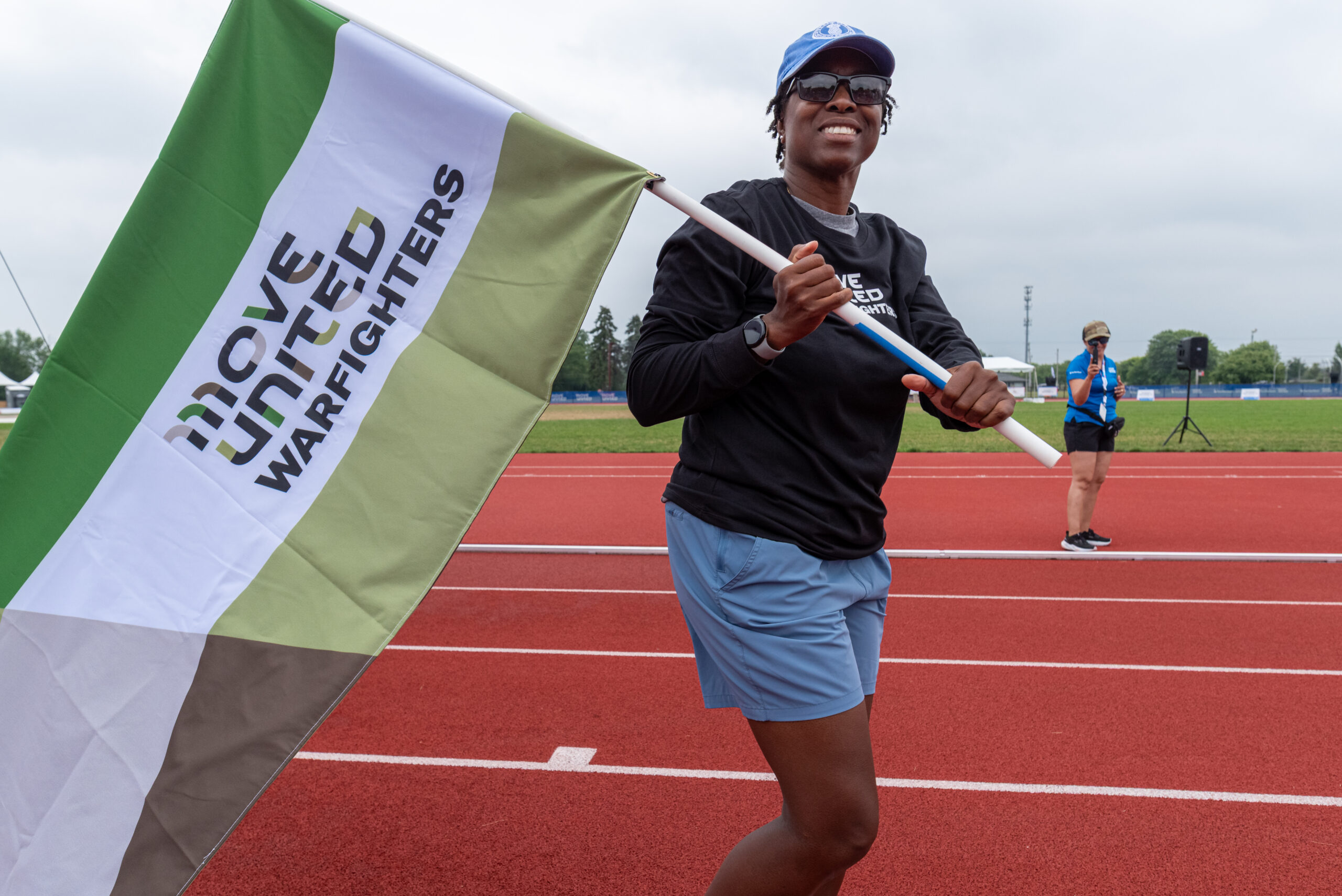 Amanda Warren walking on a track carrying a Move United Warfighters flag