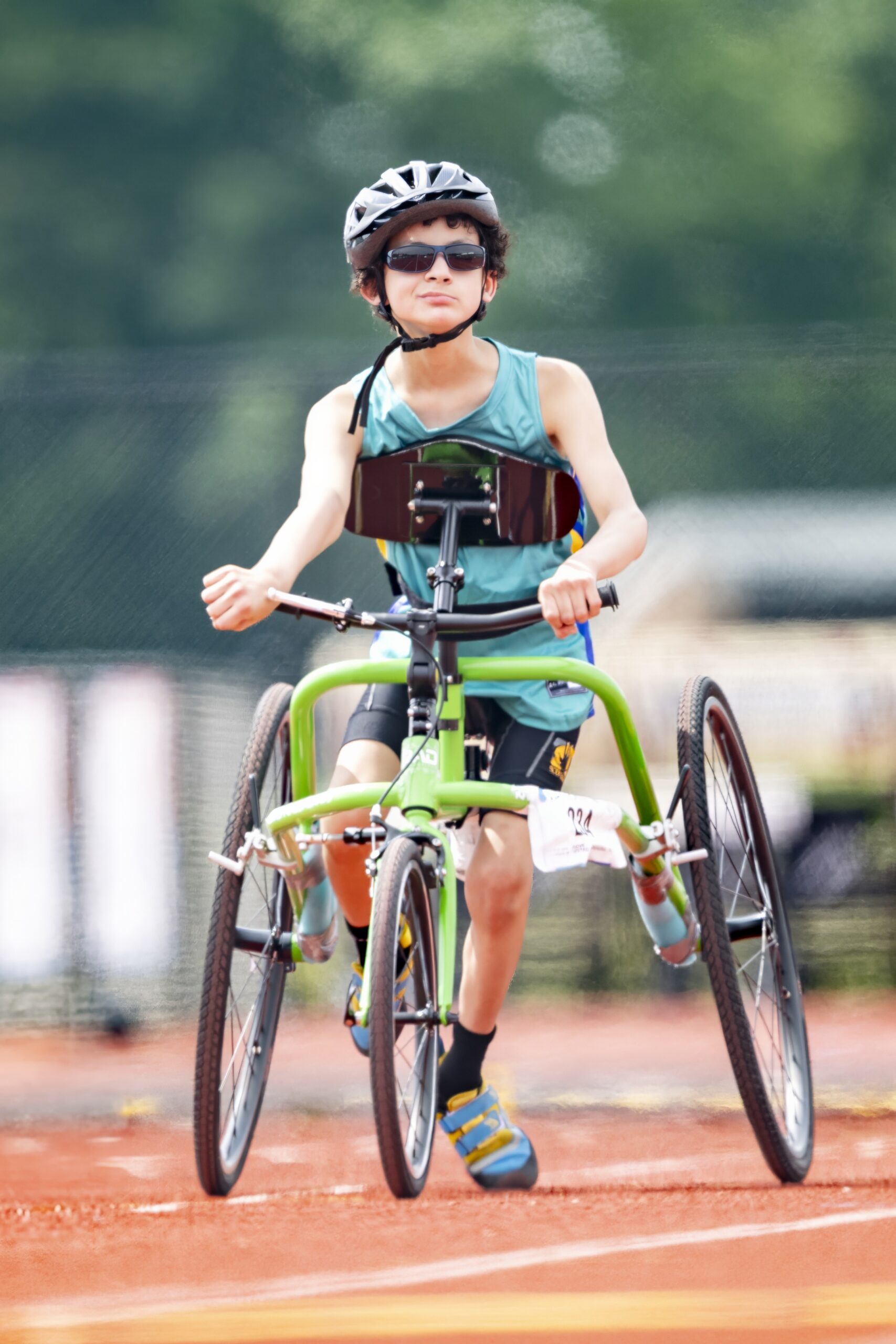 Athlete using frame runner running down long stretch of track. Athlete is wearing a green shirt, blue shoes and is using a green frame runner.