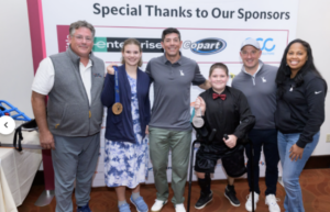 Image of six people smiling in front of event banner.