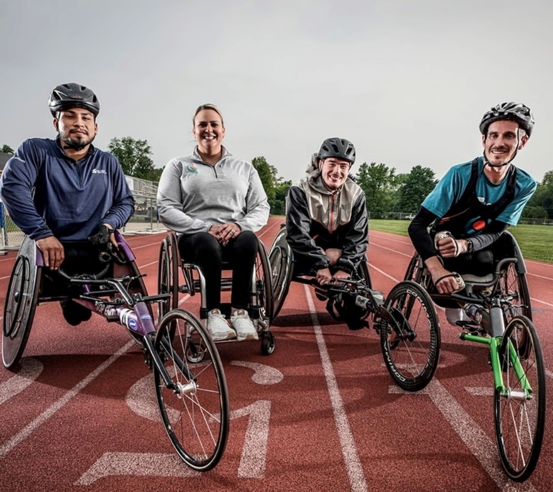 Coach Amie Day with three of her wheelchair track athletes pose on the track