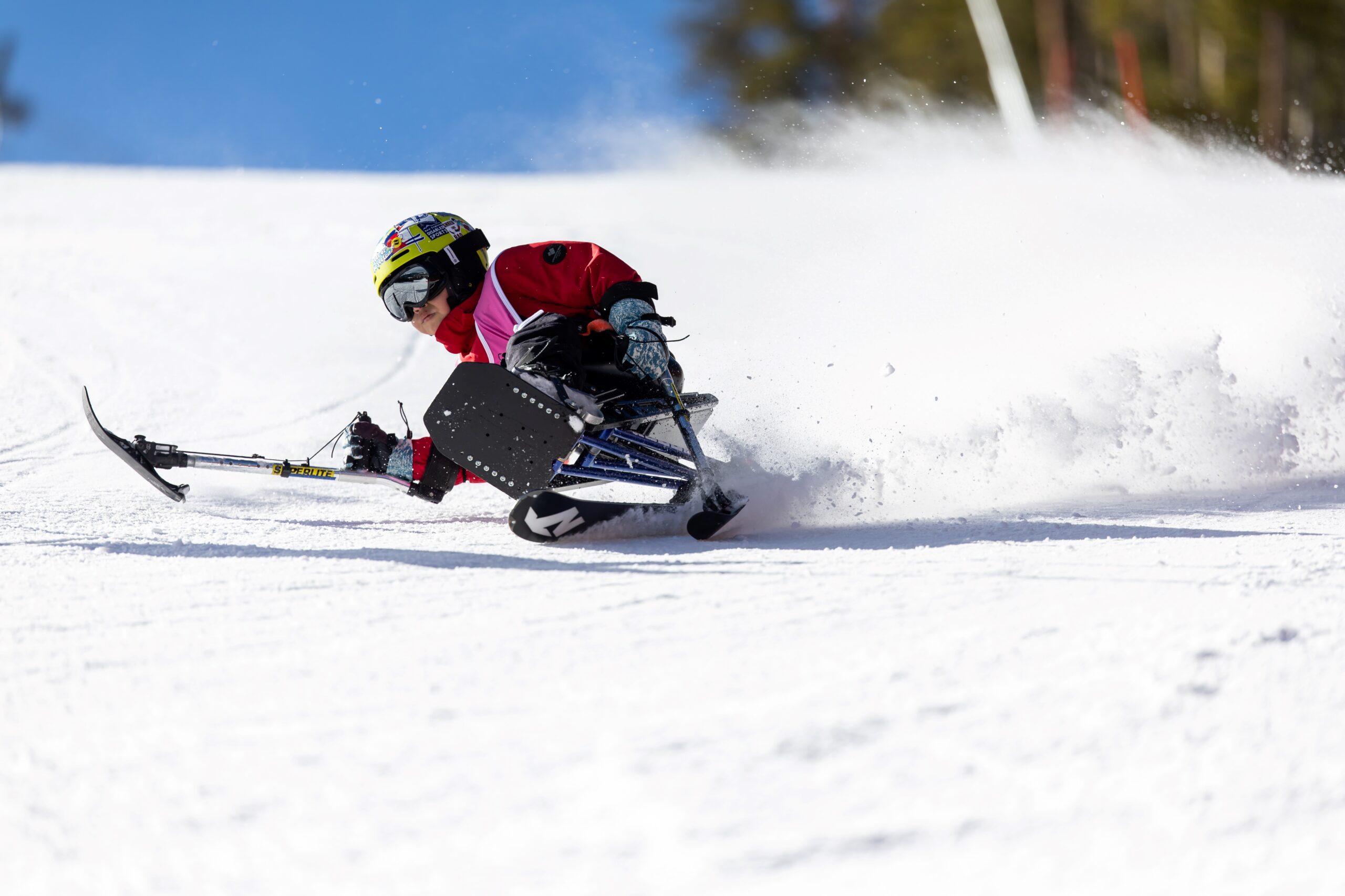 youth male athlete skiing down the slope while having snow spray up behind him