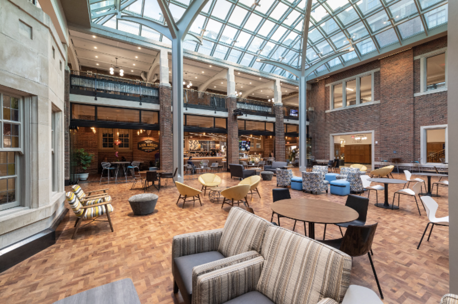 Large room with glass ceilings and multiple areas to sit and converse.