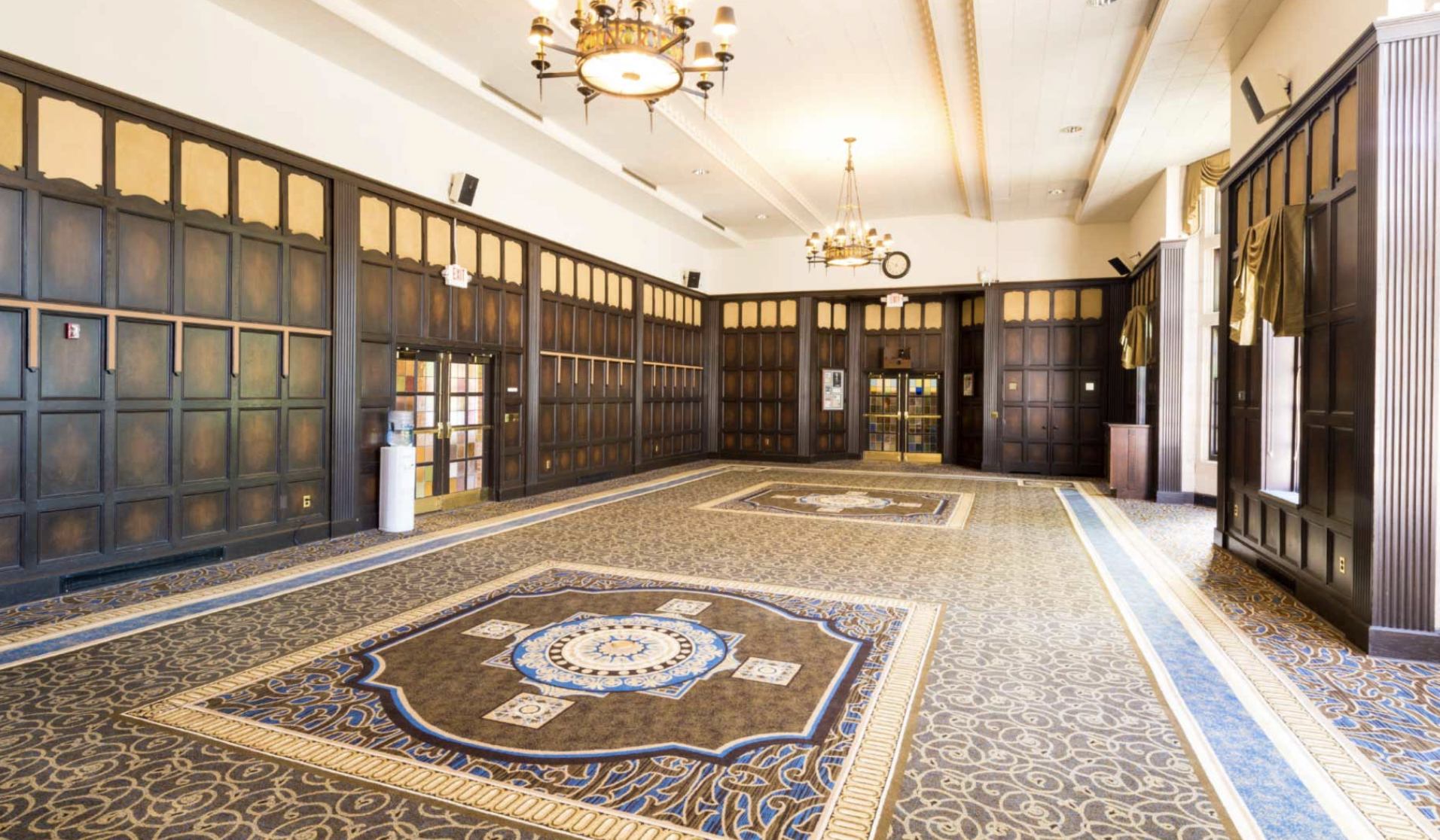 Ballroom with carpet floor, wooden accents and a chandelier.