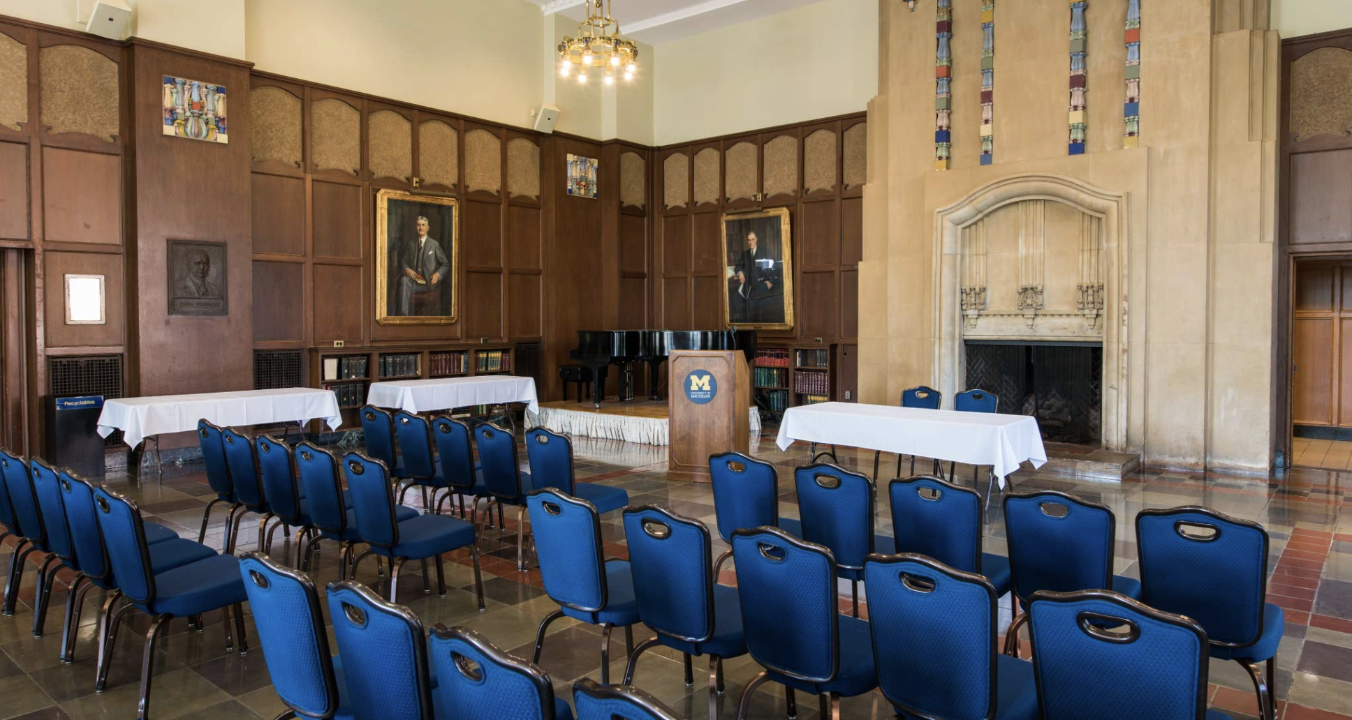 Speaker hall with tables at the front and rows of chairs in the audience.