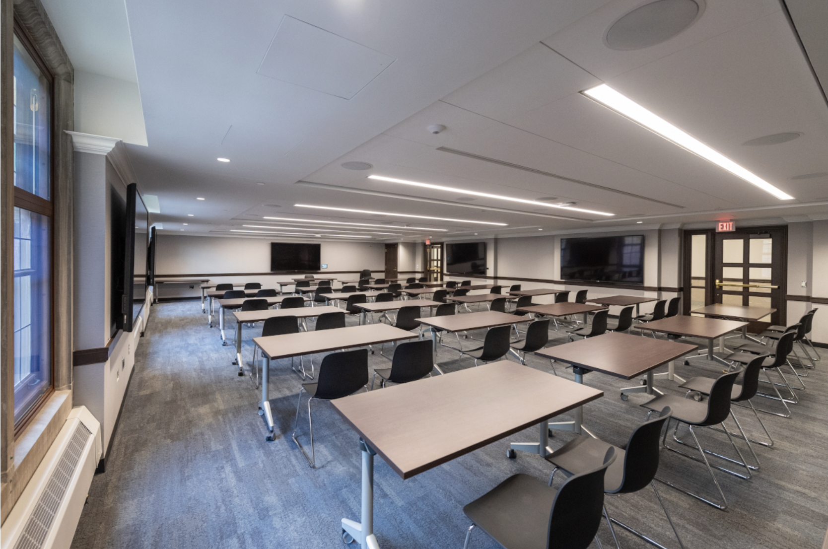 Classroom style with a board at the front and multiple rows of desks.