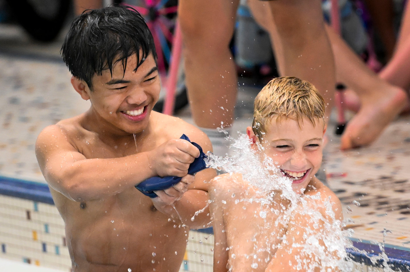 Athletes having fun on a pool deck splashing one another.