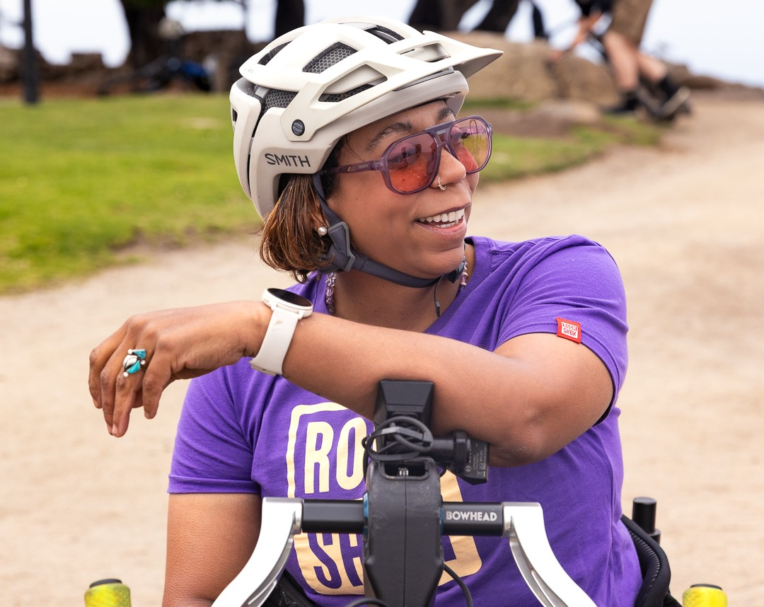 Black female adaptive athlete sitting on a mountain bike on a trail